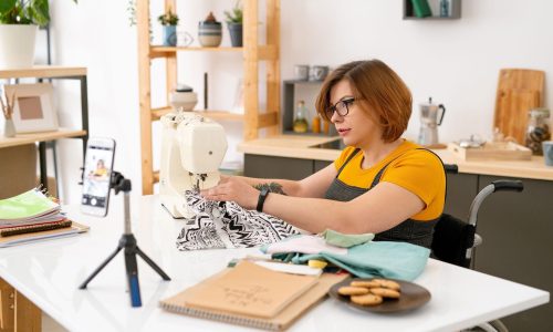 Femme en fauteuil roulant qui utilise une machine à couture lors de nos ateliers.