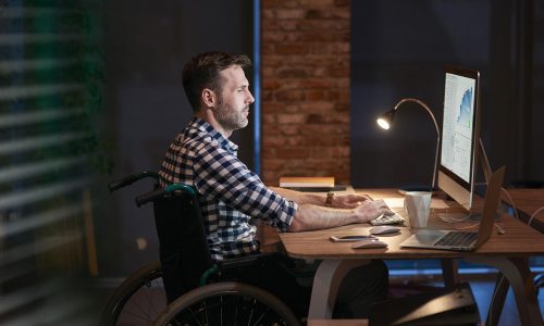 Homme en fauteuil roulant qui travaille sur un ordinateur qui réalise un site internet gratuit.